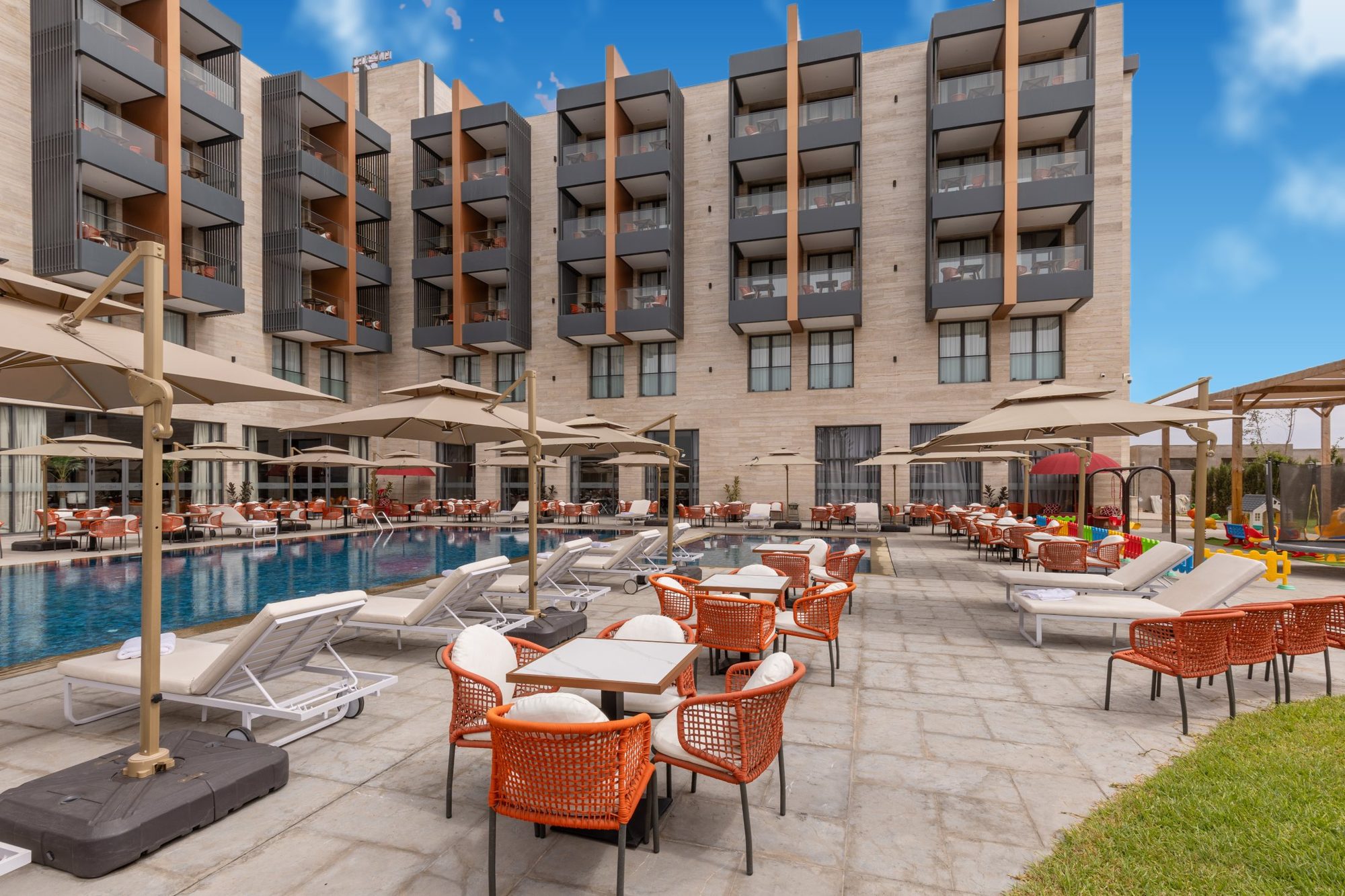 La piscine extérieure, ses parasols et la façade de l'hôtel