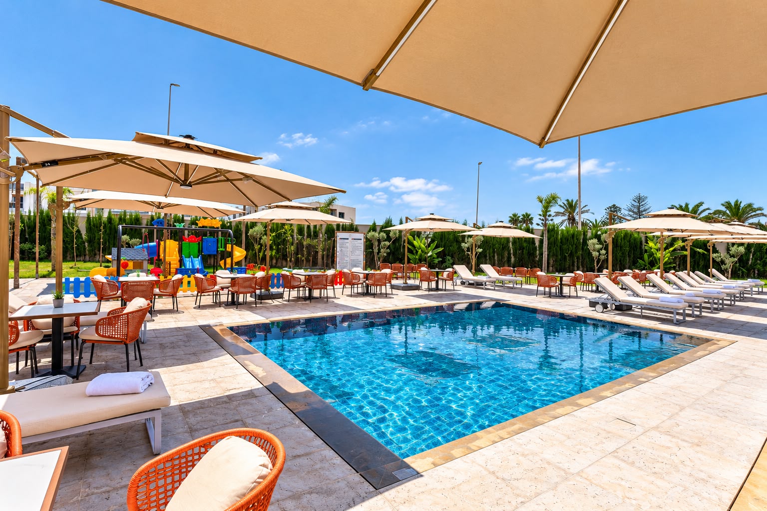 La piscine extérieure, ses parasols et la façade de l'hôtel