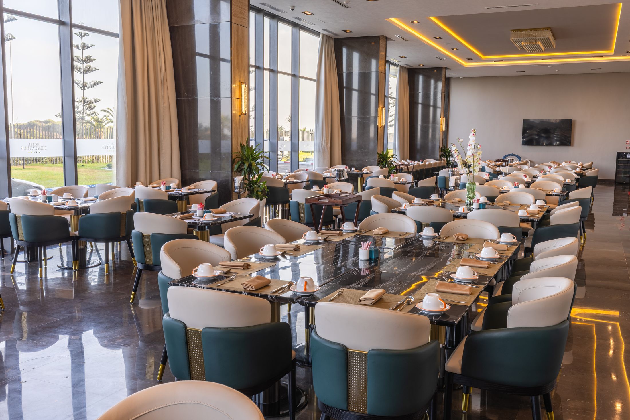 La salle du restaurant Le Méditerranéen, tables dressées face aux baies vitrées